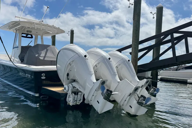 Slide: The Image of 2023 Regulator 34 Center Console boat with triple outboard engines docked at marina. - 11
