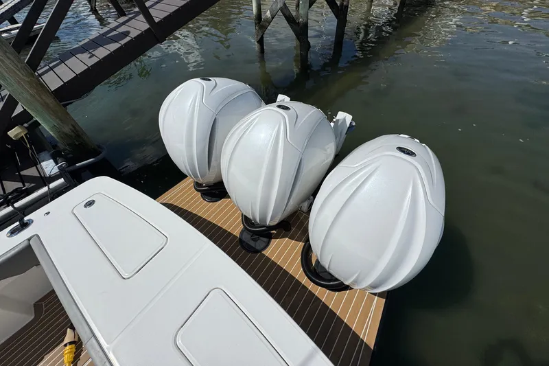 Slide: The Image of 2023 Regulator 34 Center Console with triple outboard engines docked by water. - 14