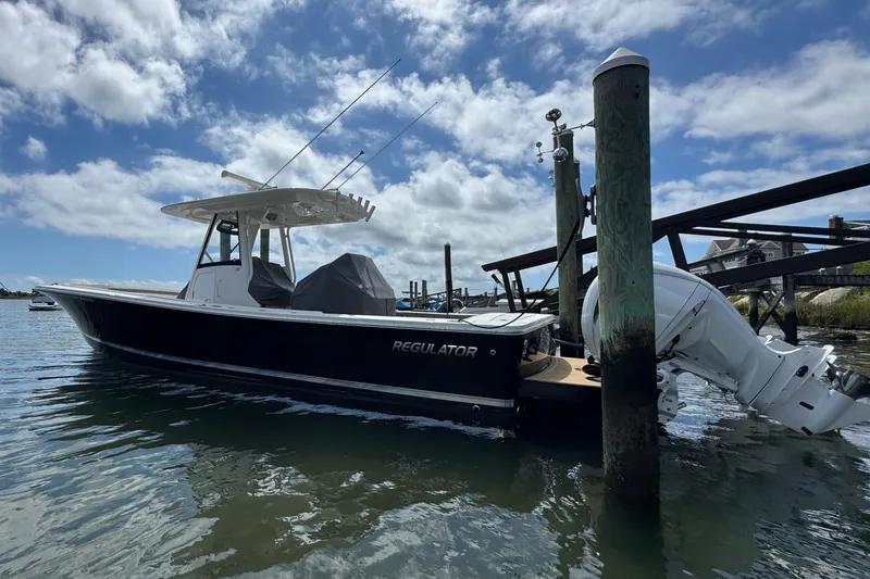Slide: The Image of 2023 Regulator 34 Center Console boat docked by waterfront homes under a blue sky. - 2