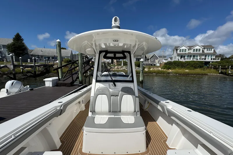 Slide: The Image of 2023 Regulator 34 Center Console boat docked by waterfront homes under blue sky. - 27