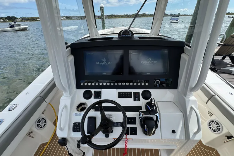 Slide: The Image of 2023 Regulator 34 Center Console boat dashboard with dual Garmin displays and steering wheel. - 53