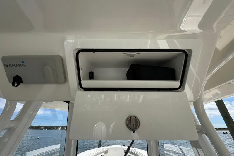 Slide: The Image of 2023 Regulator 34 Center Console storage compartment with Garmin equipment, open on a sunny day. - 57