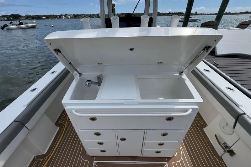 Slide: The Image of 2023 Regulator 34 Center Console boat with open storage compartment and sink on deck. - 58