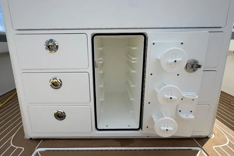 Slide: The Image of 2023 Regulator 34 Center Console storage compartment with open door and drawers on deck. - 59