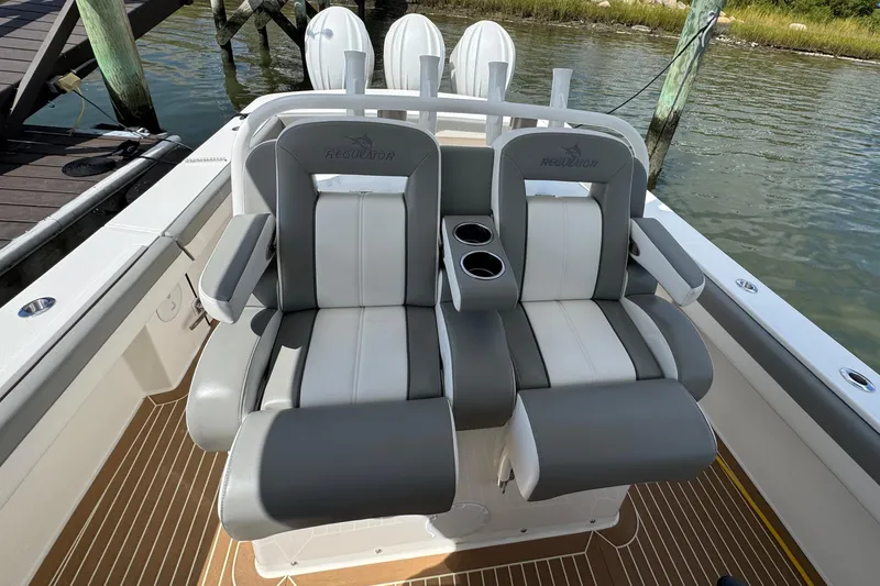 Slide: The Image of 2023 Regulator 34 Center Console boat seats with cup holders, docked by the water. - 66