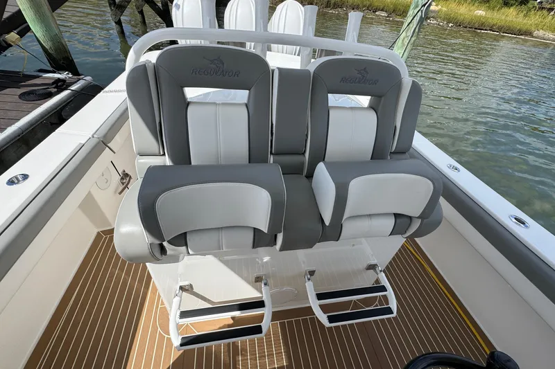 Slide: The Image of 2023 Regulator 34 Center Console boat with dual cushioned seats and footrests, docked by the water. - 67
