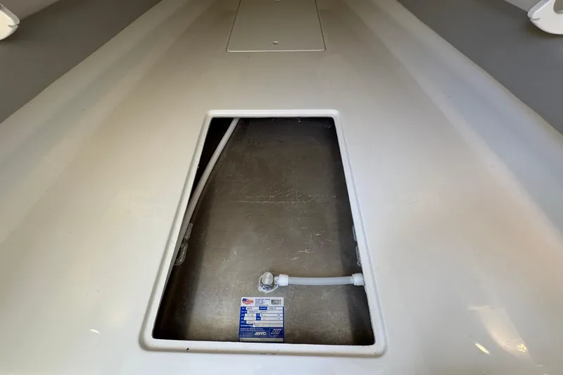 Slide: The Image of 2023 Regulator 34 Center Console storage compartment with visible label and hose connection. - 80