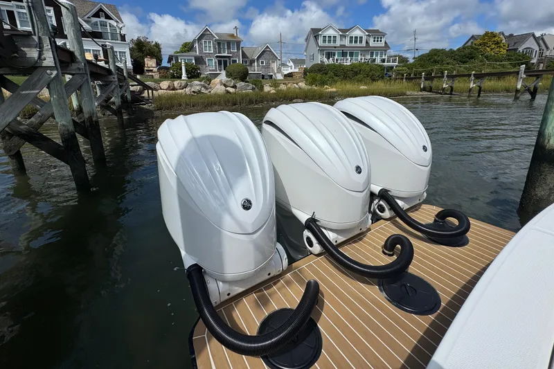 Slide: The Image of Triple outboard engines on a 2023 Regulator 34 Center Console boat, docked near coastal homes. - 84