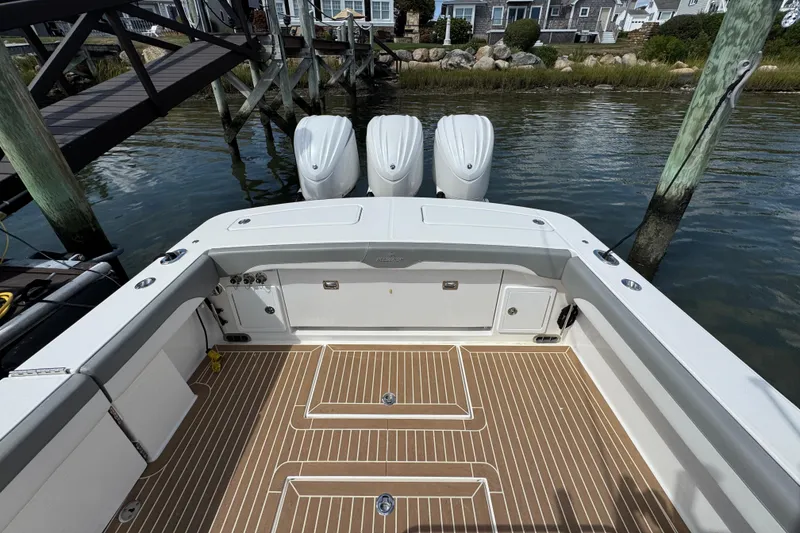 Slide: The Image of 2023 Regulator 34 Center Console boat with triple engines, docked by wooden pier. - 85