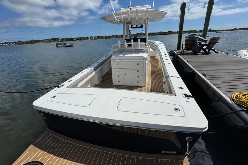 Slide: The Image of 2023 Regulator 34 Center Console boat docked by the water on a sunny day. - 91