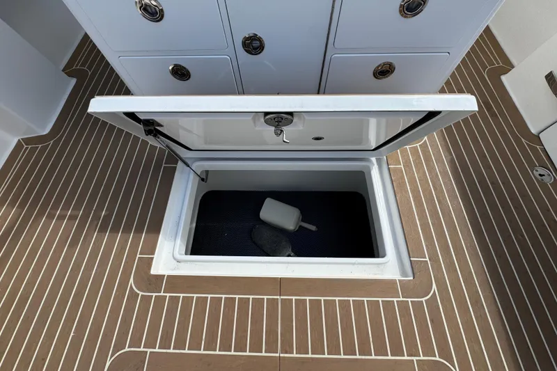 Slide: The Image of Open storage compartment on 2023 Regulator 34 Center Console boat with teak flooring. - 93