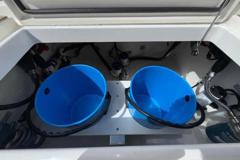 Slide: The Image of 2023 Regulator 34 Center Console storage compartment with blue buckets and marine equipment. - 97