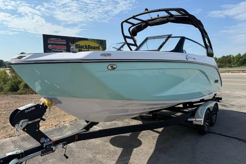 Slide: The Image of 2026 Yamaha Boats 222S on trailer, sleek design, light blue hull, sunny day. - 2