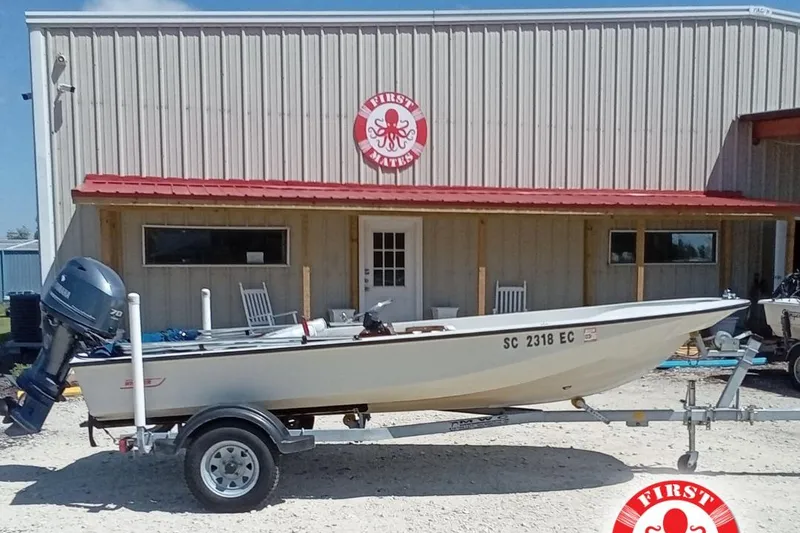 The Image of 1985 Boston Whaler 150 Sport boat on trailer outside a building with red roof. - 1