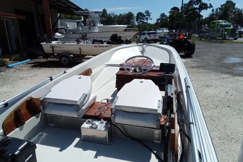 Slide: The Image of 1985 Boston Whaler 150 Sport boat interior with steering wheel, seats, and equipment in a marina. - 10