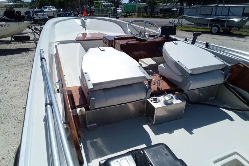 Slide: The Image of 1985 Boston Whaler 150 Sport boat interior with seating and steering wheel, parked outdoors. - 11