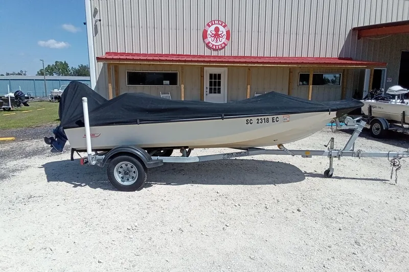 Slide: The Image of 1985 Boston Whaler 150 Sport boat on trailer, covered, outside a building. - 15