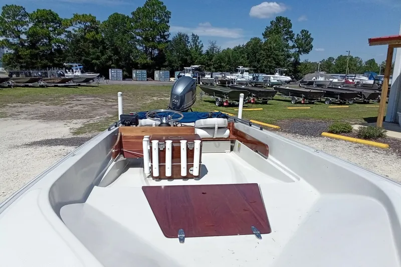 Slide: The Image of 1985 Boston Whaler 150 Sport boat with outboard motor, parked outdoors on a sunny day. - 5