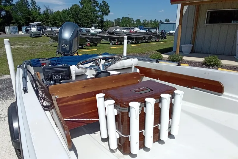 Slide: The Image of 1985 Boston Whaler 150 Sport boat with wooden console and rod holders, parked outdoors. - 6