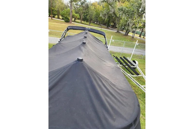 Slide: The Image of Covered 2022 Avalon GS Rear Fish boat in a grassy area with trees. - 14