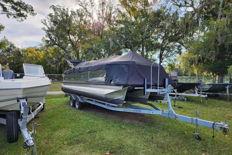 Slide: The Image of 2022 Avalon GS Rear Fish boat on trailer, covered, surrounded by trees. - 17