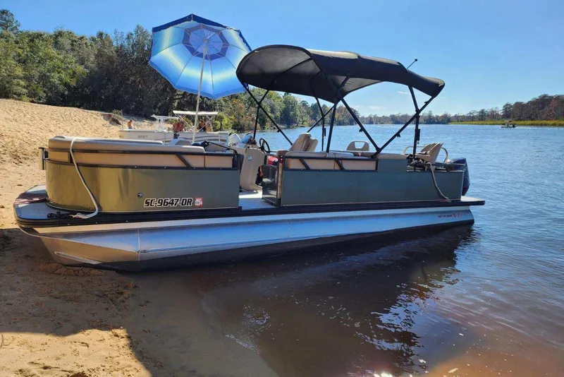 Slide: The Image of 2022 Avalon GS Rear Fish pontoon boat docked on a sandy riverbank. - 24