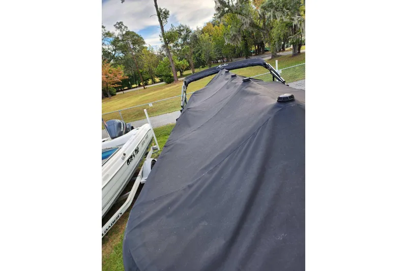 Slide: The Image of 2022 Avalon GS Rear Fish boat covered, parked outdoors near trees. - 27