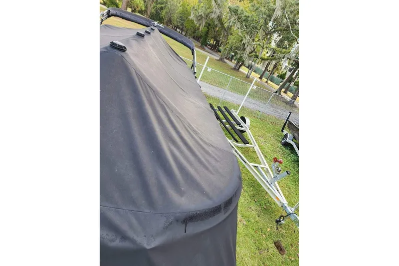 Slide: The Image of Covered Avalon GS Rear Fish 23' boat on trailer, parked on grass near trees. - 6