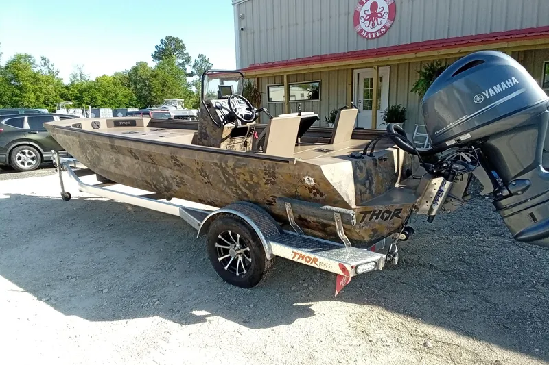 Slide: The Image of 2025 Thor 1900 Lake Hammer boat with Yamaha motor on a trailer, parked outdoors. - 11