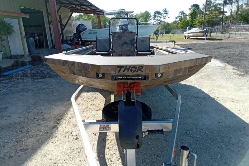 Slide: The Image of 2025 Thor 1900 Lake Hammer boat on trailer, parked outdoors near a workshop. - 3