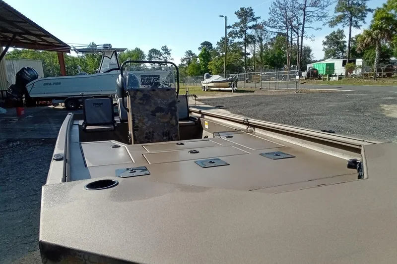 Slide: The Image of 2025 Thor 1900 Lake Hammer boat in a yard, surrounded by trees and other boats. - 4