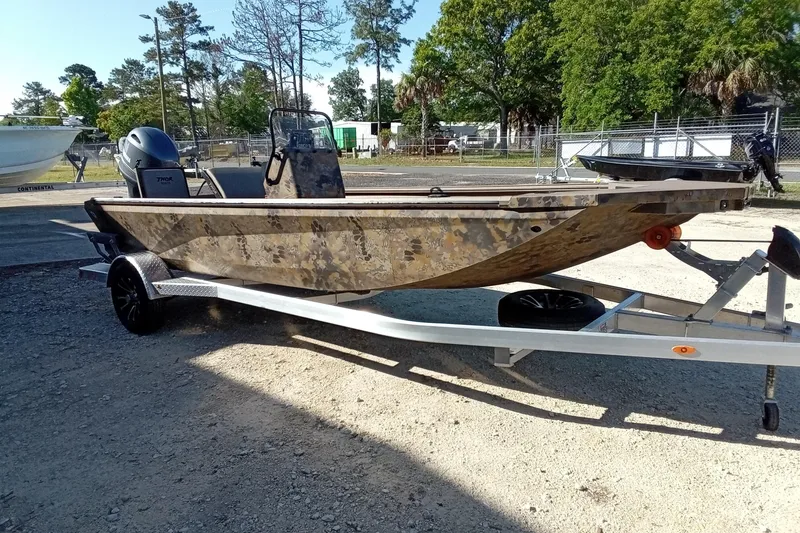 Slide: The Image of 2025 Thor 1900 Lake Hammer boat on trailer, camo design, parked outdoors. - 5