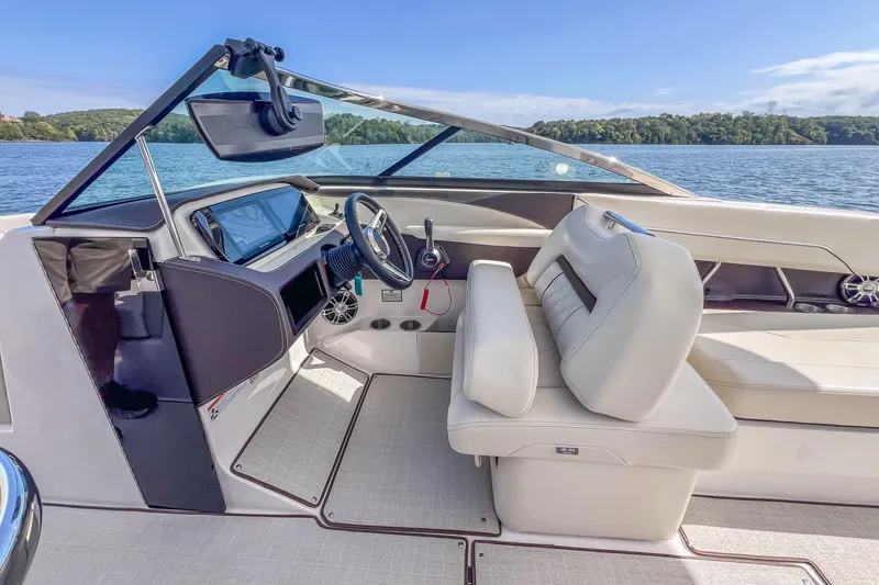 Slide: The Image of 2022 Regal LS6 boat interior with modern dashboard and comfortable seating on a sunny lake. - 25