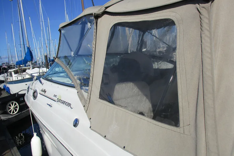 Slide: The Image of 2000 Sea Ray 240 Sundancer boat docked with beige canopy and clear windows. - 6