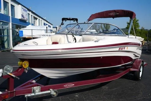 The Image of 2011 Tahoe Q5SI boat on trailer, white and maroon, parked outside showroom. - 1