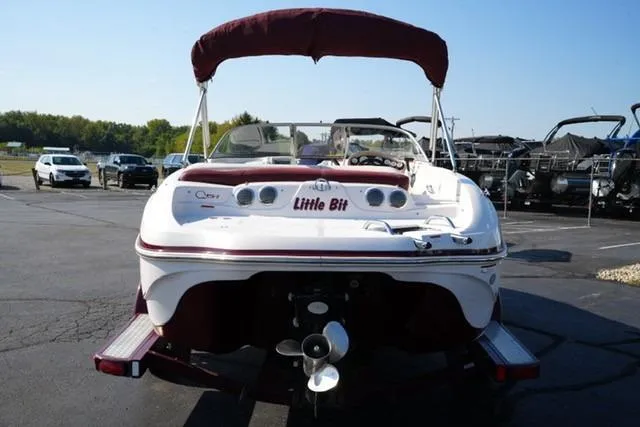 Slide: The Image of 2011 Tahoe Q5SI boat with maroon canopy, parked on asphalt, rear view. - 4