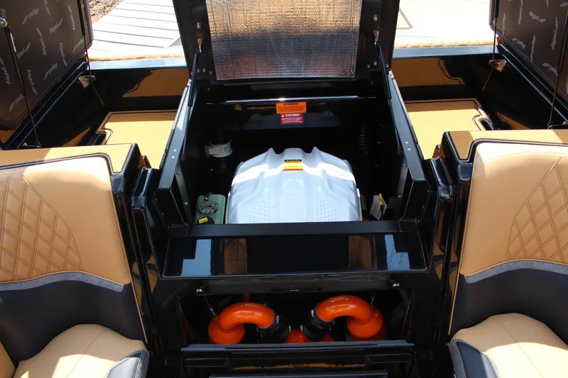 Slide: The Image of 2026 Tigé 24RZX boat engine compartment with tan seating and orange components. - 23