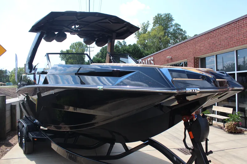 Slide: The Image of 2026 Tigé 24RZX boat in showroom, sleek black design, parked on trailer. - 9
