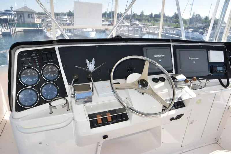 Slide: The Image of 1996 Bertram 36' Convertible helm with gauges, steering wheel, and Raymarine displays in a marina setting. - 5