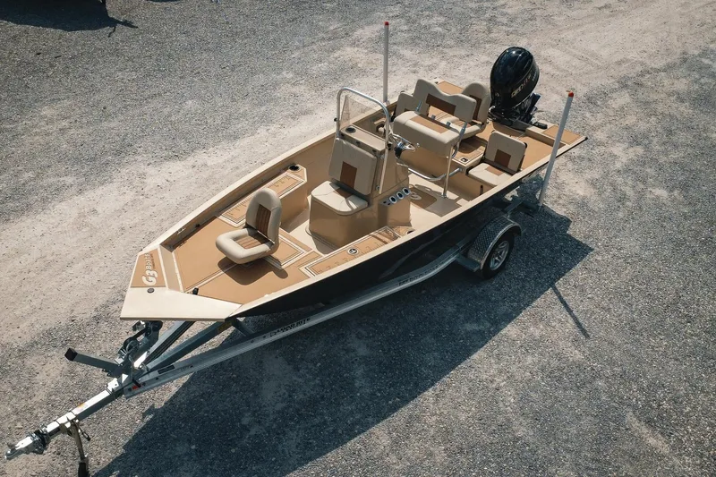 Slide: The Image of 2025 G3 Bay 19 GX boat on trailer, beige interior, parked on gravel. - 2