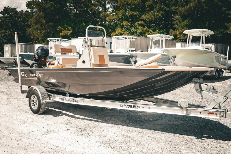 Slide: The Image of 2025 G3 Bay 19 GX boat on trailer, parked outdoors with other boats. - 6