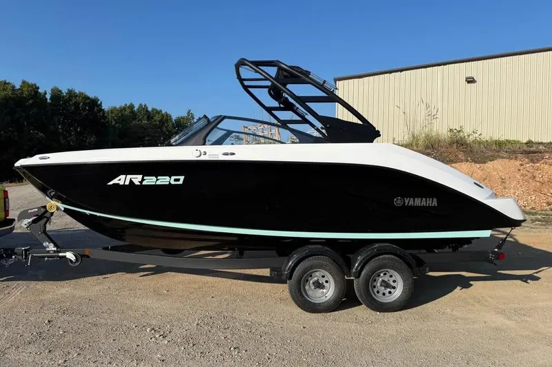 The Image of 2026 Yamaha Boats AR220 on trailer, black and white design, parked outdoors. - 0
