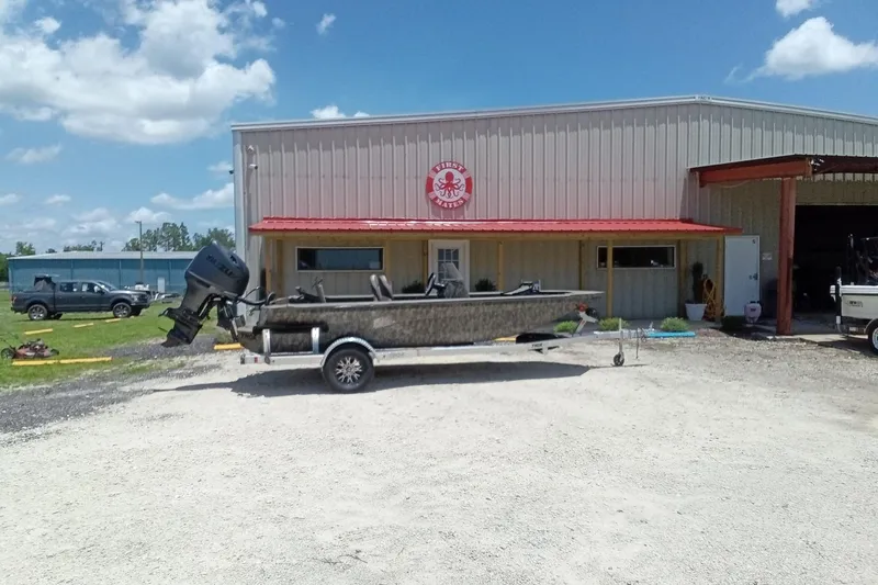 Slide: The Image of Boat on trailer outside a metal building under a blue sky. - 2