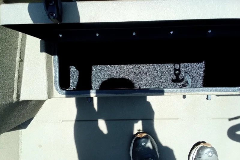 Slide: The Image of Open storage compartment in 2026 Thor 1900 Lake Hammer SC boat, with visible shadow and footwear. - 23
