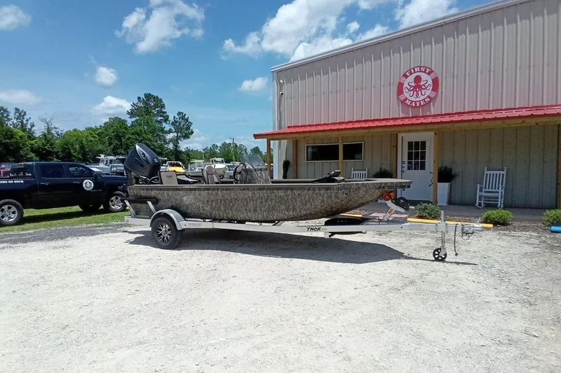 Slide: The Image of 2026 Thor 1900 Lake Hammer SC boat on trailer outside a building under a blue sky. - 5