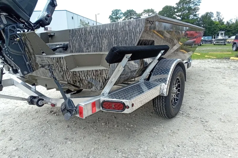 Slide: The Image of 2026 Thor 1754 Timber Hammer boat on a trailer, parked on gravel. - 16