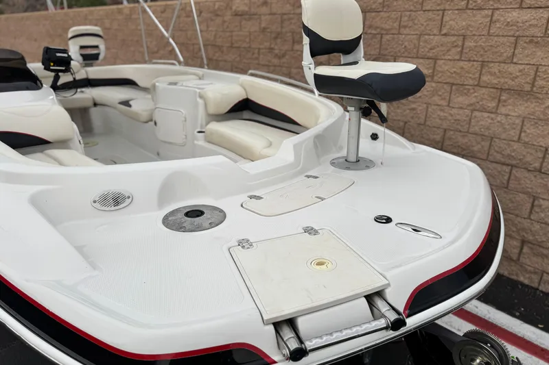 Slide: The Image of 2014 Tahoe 215 boat interior with seating and fishing chair, parked near a brick wall. - 11
