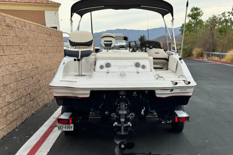 Slide: The Image of 2014 Tahoe 215 boat parked on a road, rear view with seating and controls visible. - 4