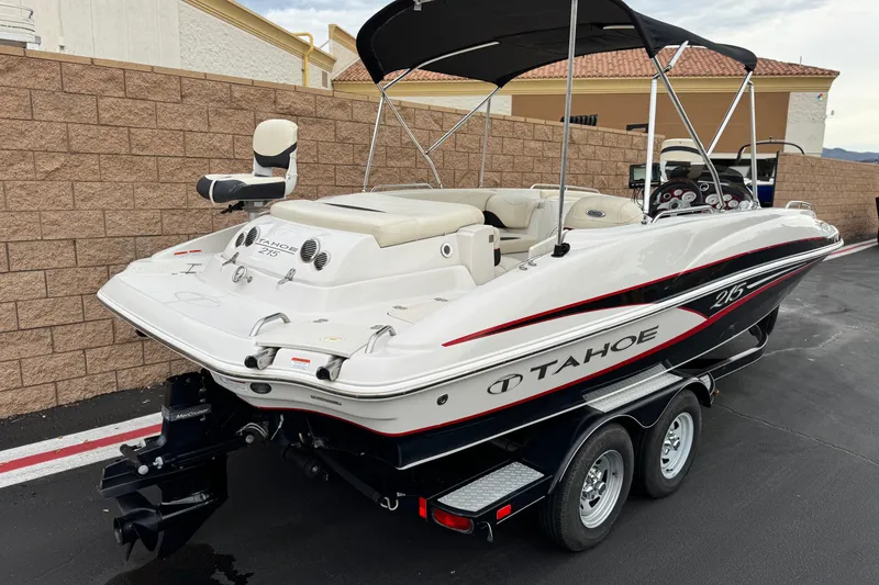Slide: The Image of 2014 Tahoe 215 boat on trailer, white with black and red accents, parked outdoors. - 5