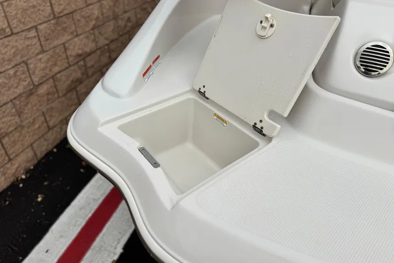 Slide: The Image of 2014 Tahoe 215 boat storage compartment with open hatch, near brick wall. - 7